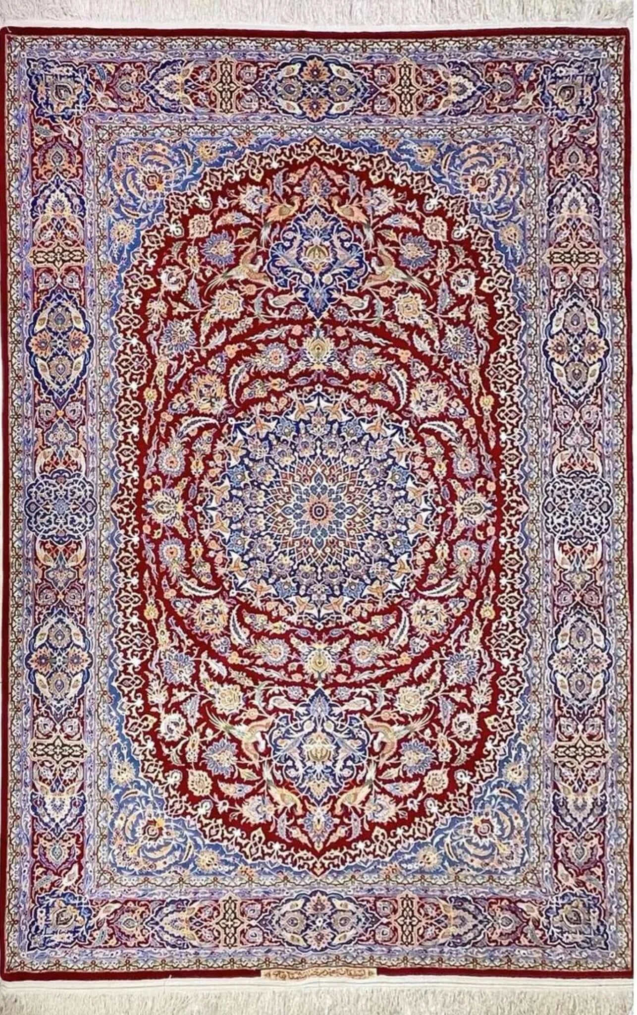 Detailed view of the Isfahan Persian carpet's central medallion with intricate floral patterns in red, blue, and ivory.